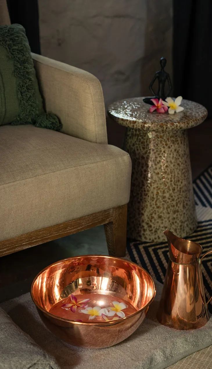 Spa chair with a copper foot bath and flowers